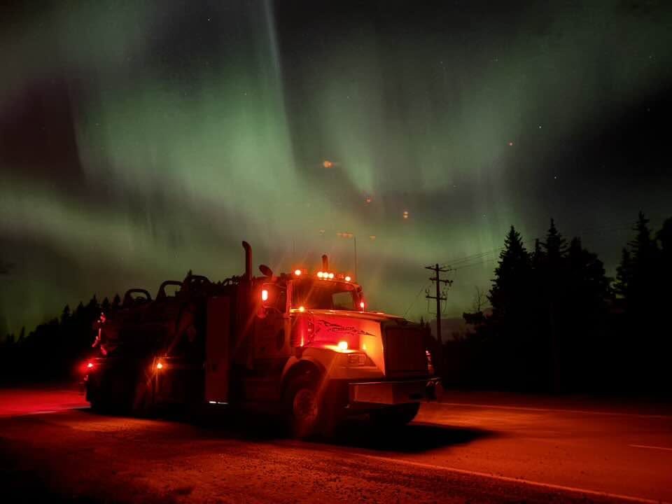 Mateo vacuum truck at night under the northern lights, running lights glowing