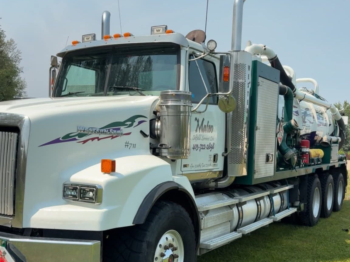 Close view of a Mateo Western Star vacuum truck cab, chrome stacks and green deck
