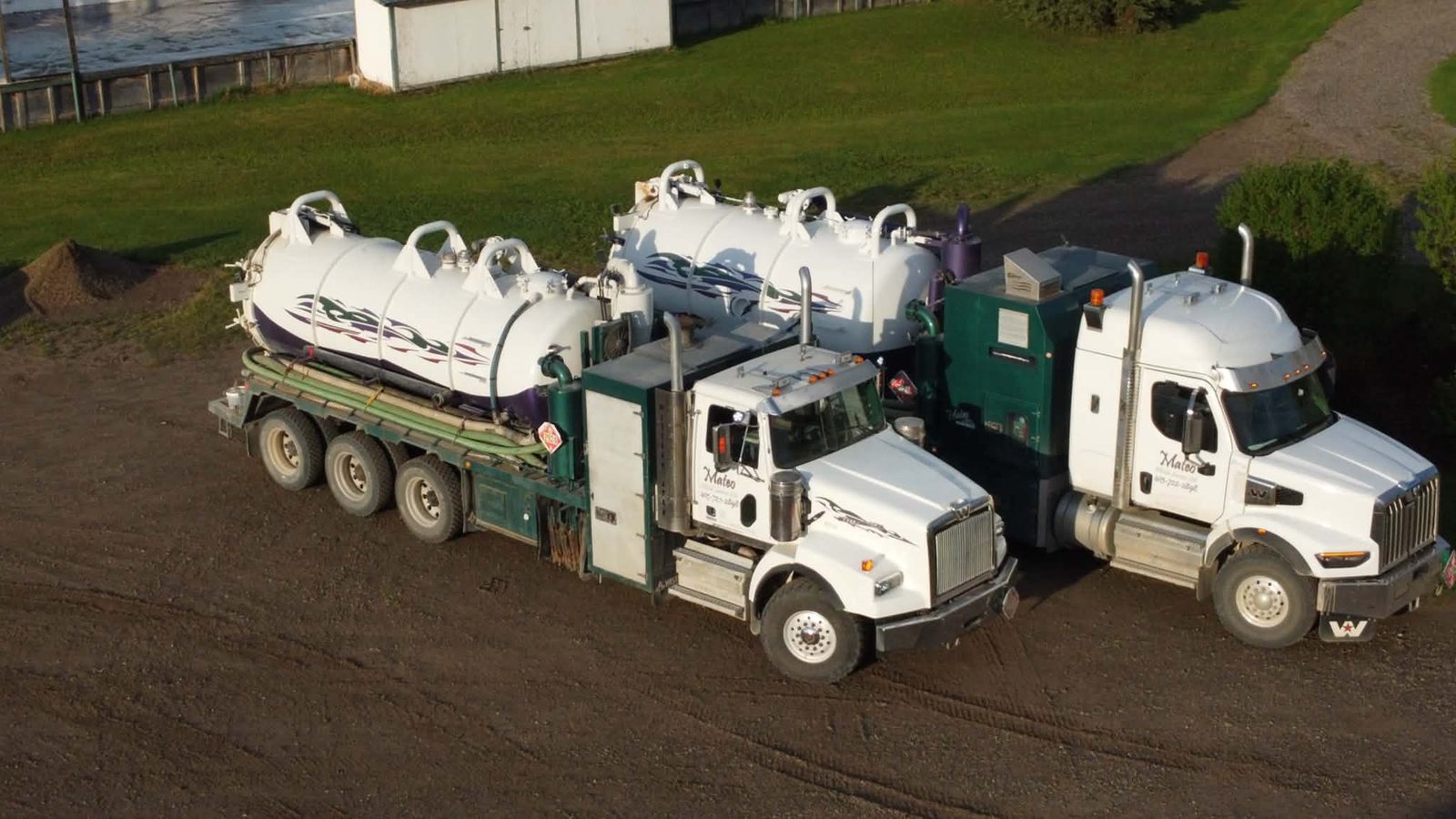 Two Mateo vacuum trucks parked side by side on the gravel yard in Caroline, seen from above