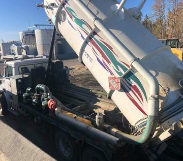 Mateo vacuum truck with its tank tipped up, unloading at an oilfield tank site